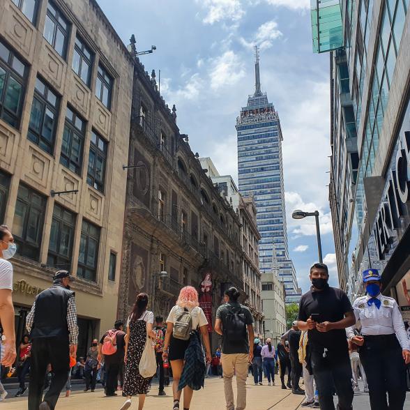 People walking on a city street between tall buildings.
