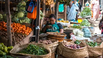 Seller in a Kenyan food market on her phone 