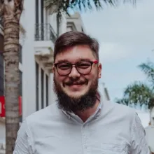 White man with beard and glasses smiling at the camera.
